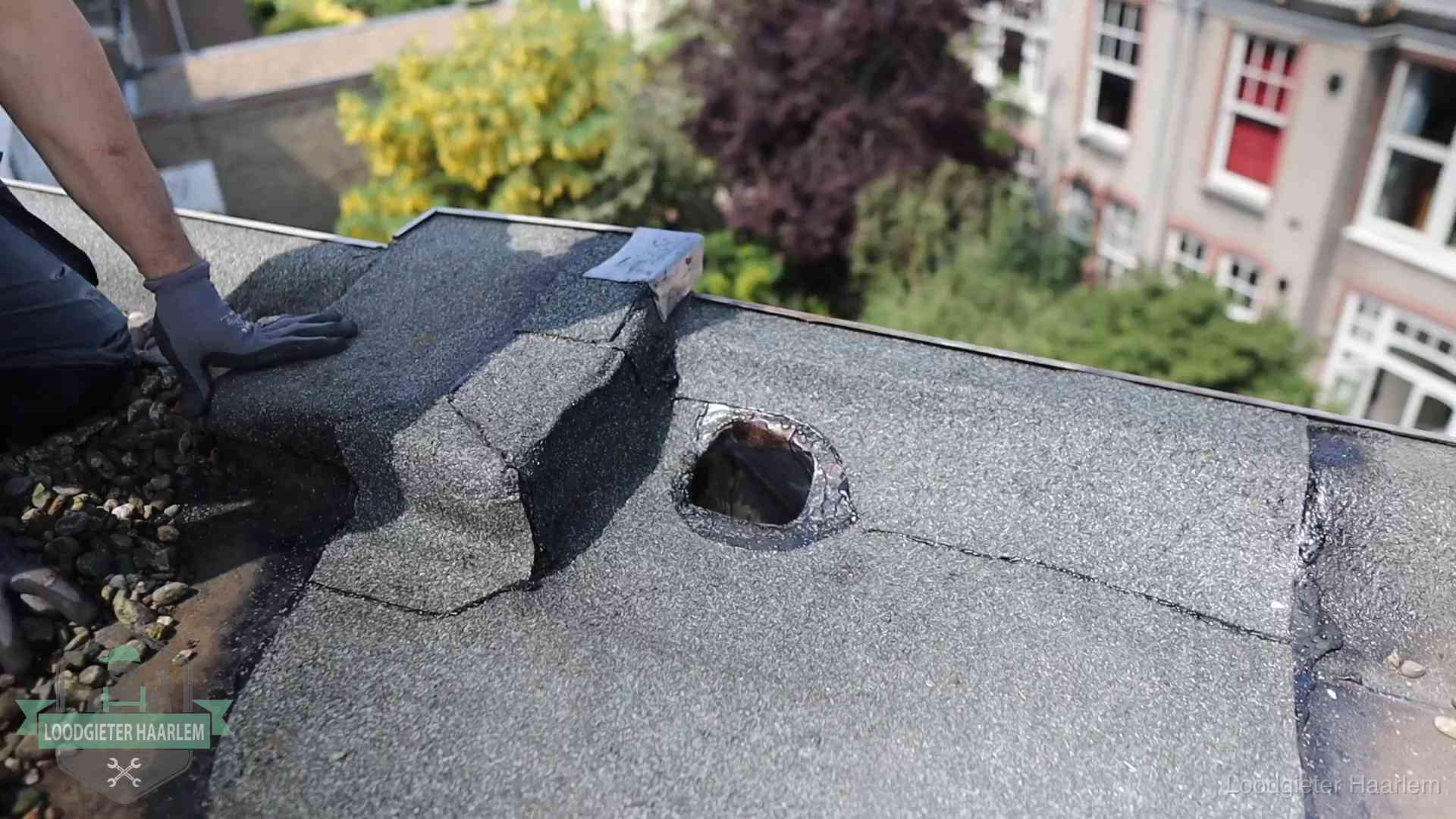 Loodgieter inspecteert een beschadigd bitumen plat dak tijdens een daklekkage-inspectie in Haarlem