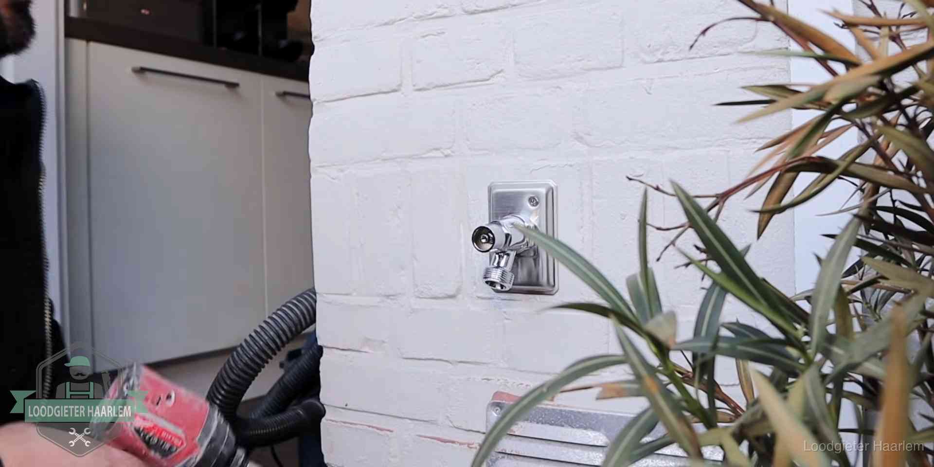 Chromen kraan op een muurplaat bij een woning in Haarlem, dichtdraaien is stap een van de lektest