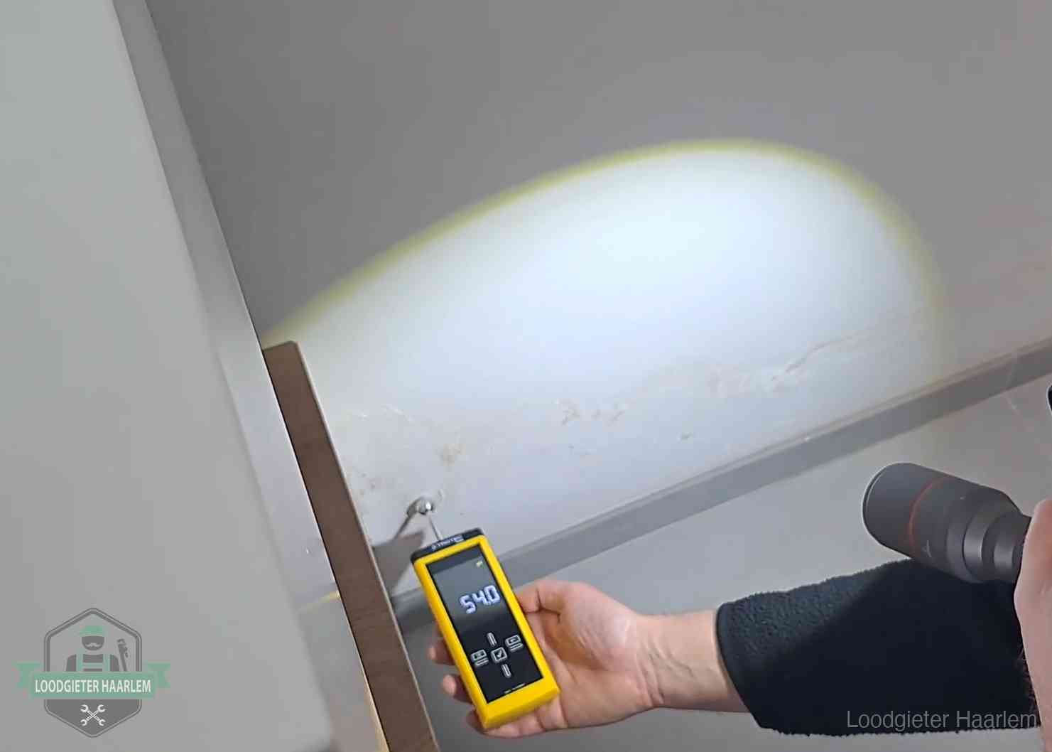 Vochtmeter tegen een natte wand met lekkagesporen in Haarlem