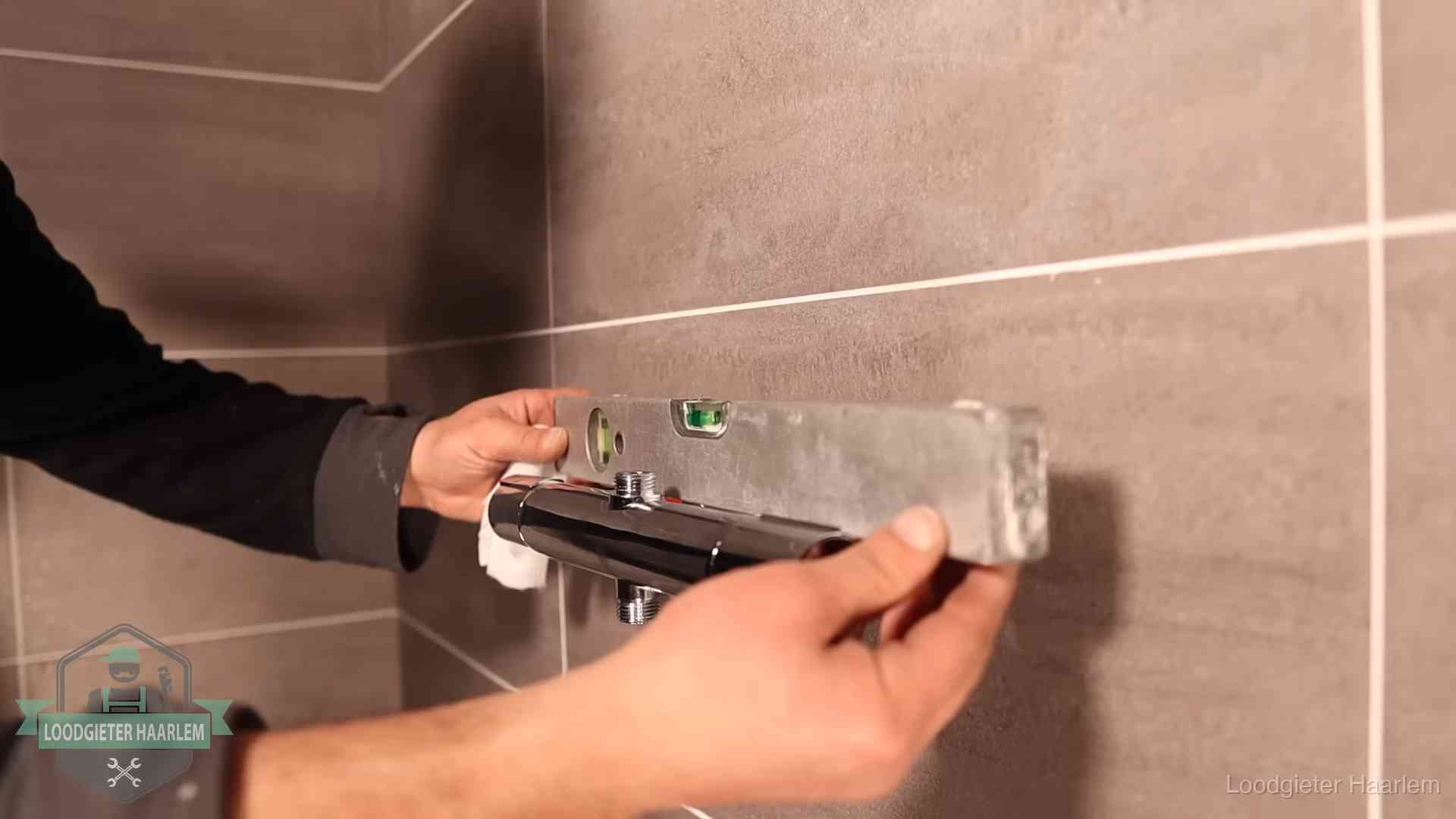 Loodgietersbedrijf voor sanitair in Haarlem Loodgieter lijnt een douchekraan uit met een waterpas in een woning in Haarlem