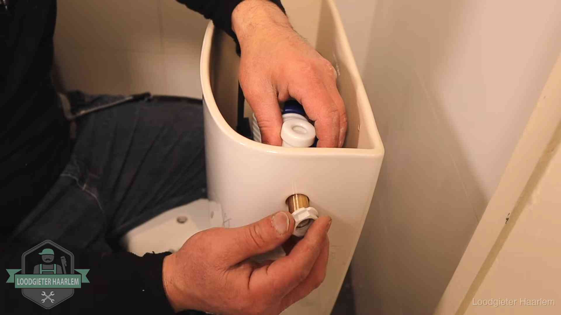 Loodgieter monteert de vlotterkraan van een stortbak bij een toilet in Haarlem