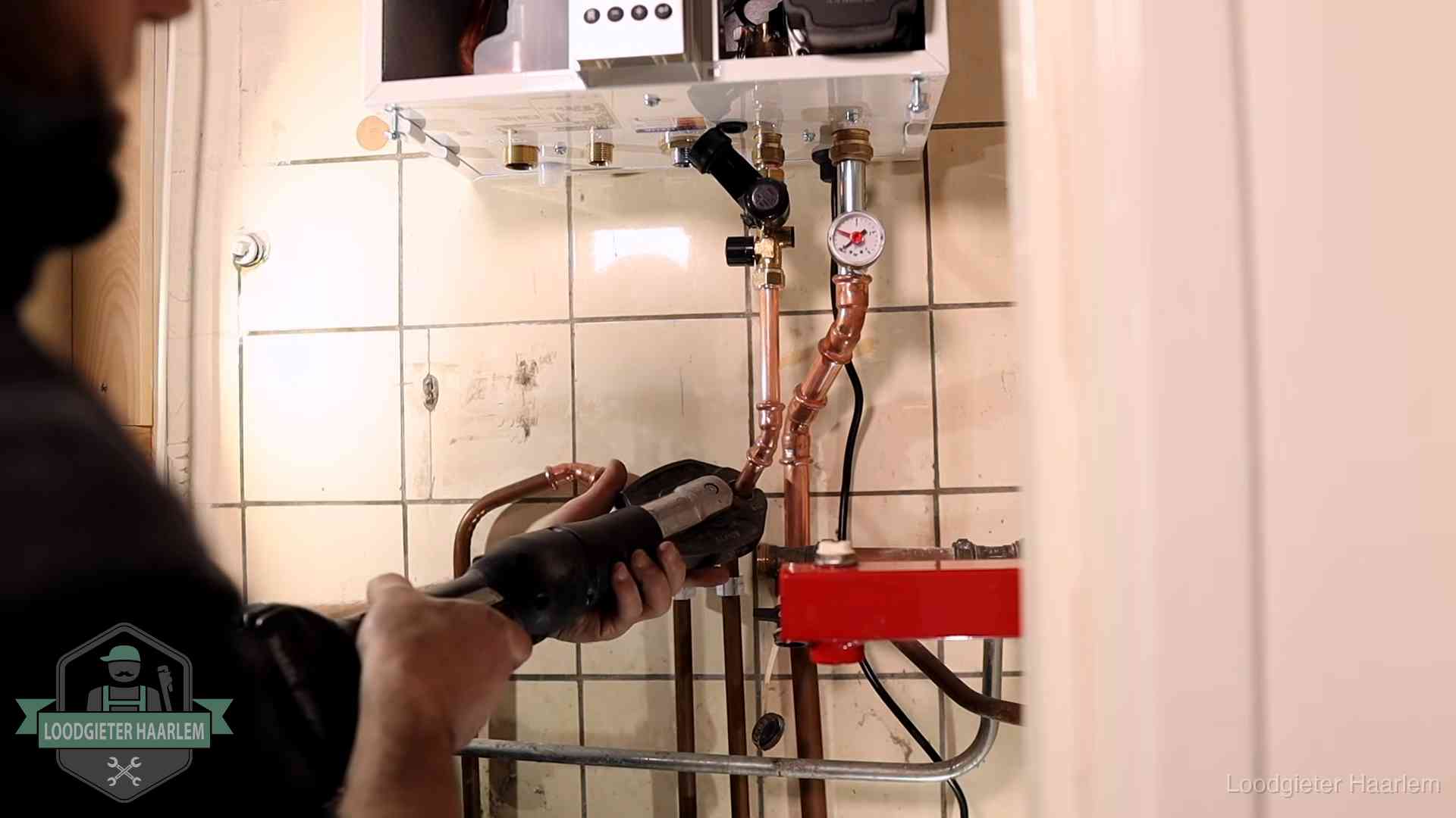 Cv-ketel onderhoud in Haarlem Monteur werkt aan de leidingen onder een cv-ketel in Haarlem
