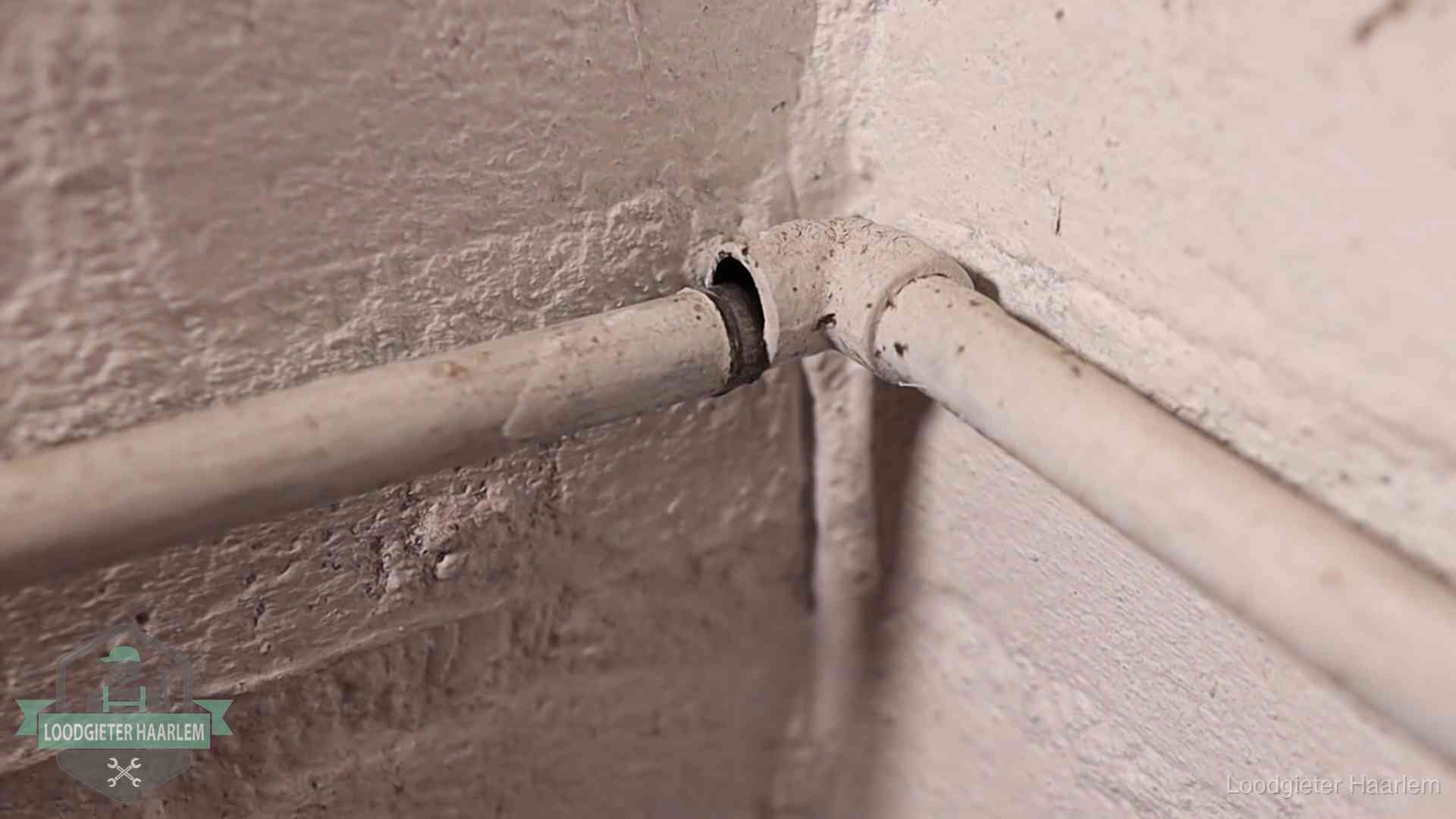 Oude geverfde waterleiding met een losliggende fitting in een woning in Haarlem