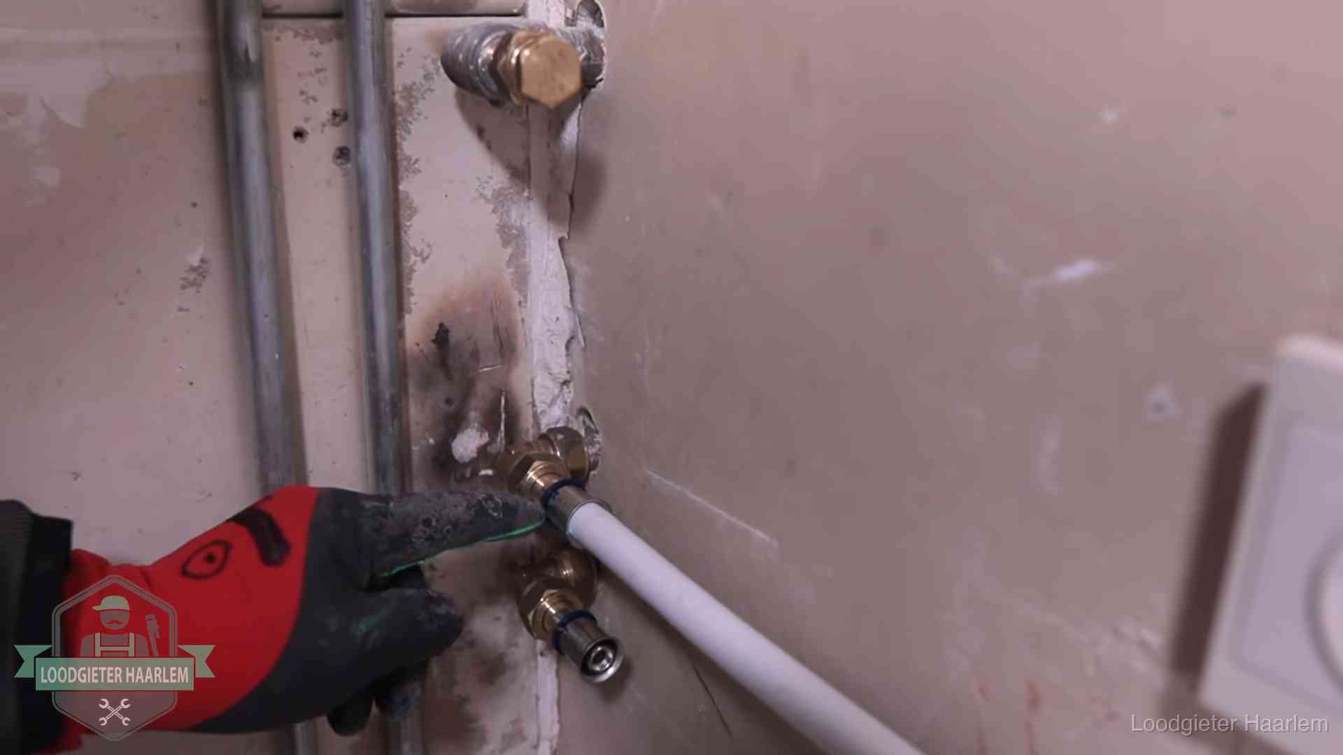 Garantie op loodgieterswerk in Haarlem Loodgieter wijst de persfitting op nieuwe muuraansluitingen aan in een woning in Haarlem