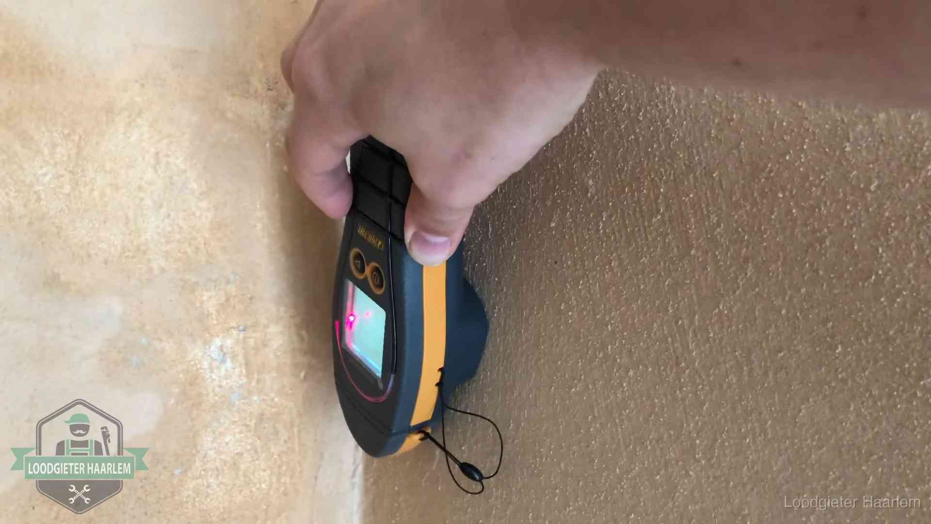 Vochtmeter tegen een muur met vochtplekken tijdens het opsporen van een daklekkage in Haarlem