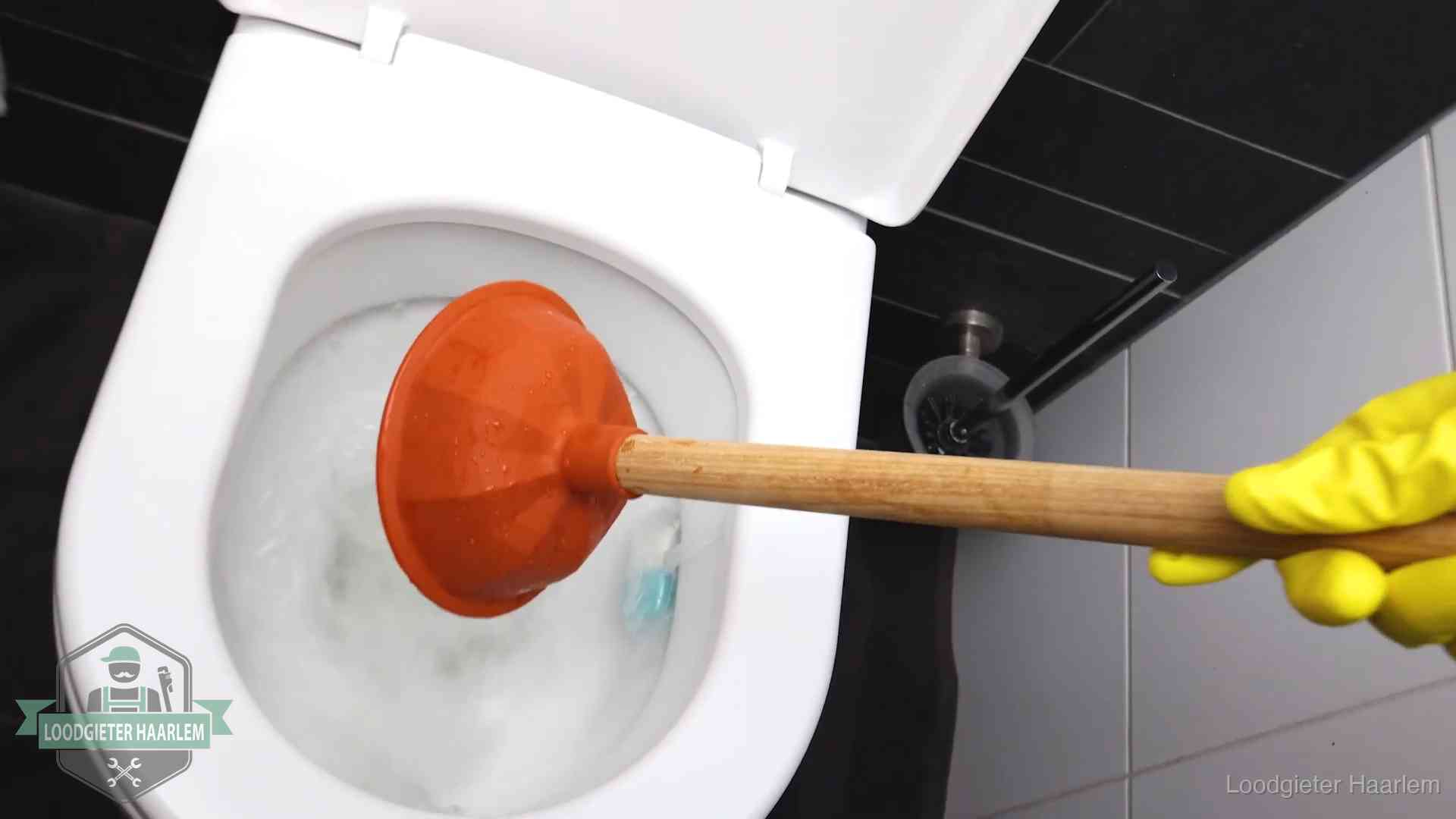 Plopper wordt in de wc-pot gedrukt bij het ontstoppen van een toilet in Haarlem