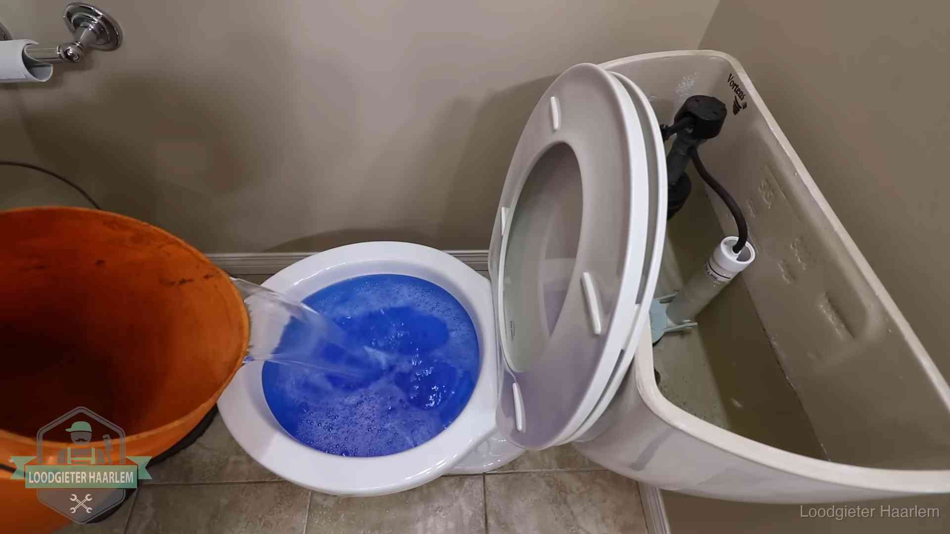 Water bij de wc-pot wordt met een emmer weggewerkt om schade te beperken in Haarlem